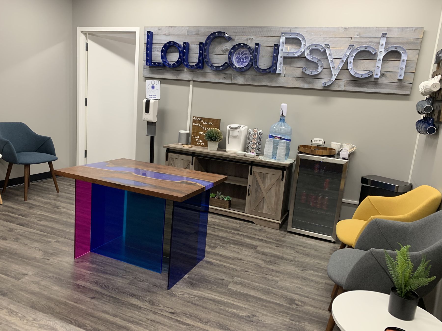 The LouCouPsych waiting room in Sterling, with the marquee sign, a drink station, and colorful chairs